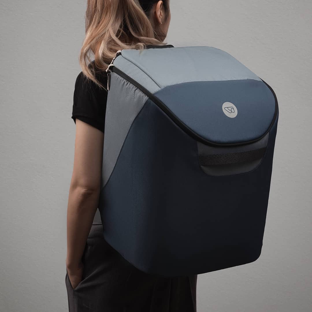 Person wearing a large blue and gray backpack on a plain background