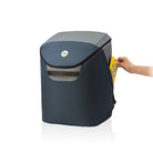 Blue trash bin with a hand placing a yellow bag inside on a white background