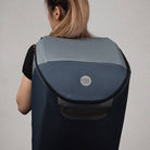 Person wearing a gray and black backpack with a visible brand logo on a plain background