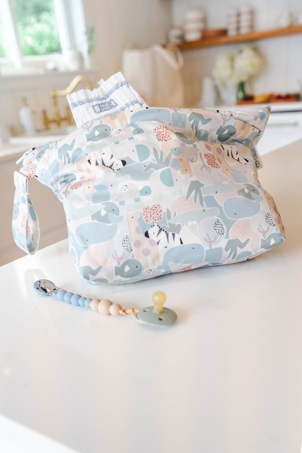 Patterned diaper bag with a pacifier on a white surface