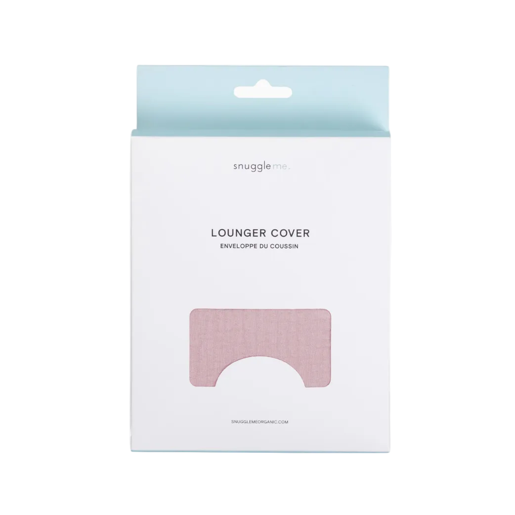 A boxed product package for a Snuggle Me Lounger Cover, shown against a clean white background. The package is white with a pale blue hanging tab at the top and a pink fabric insert visible through a die-cut window on the front.