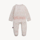 A baby footed sleeper with long sleeves and an all-over small red and green floral print on a white background, featuring a pink ruffle detail at the waist.