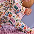 Child wearing colorful pajama sleeves with cityscape design on a purple carpet.