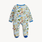 A baby footed sleeper with long sleeves and an all-over whimsical castle and dinosaur pattern on a light blue background, finished with solid blue trim at the collar, cuffs, and toes.