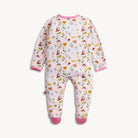 A baby footed sleeper in a light pink color with a colorful woodland pattern of trees, birds, and mushrooms, finished with solid pink trim on the collar, cuffs, and toes.