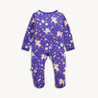 A baby footed one-piece sleeper in purple with a whimsical space print featuring white unicorns, fairies, stars, planets, and rockets, displayed flat against a light off-white background.