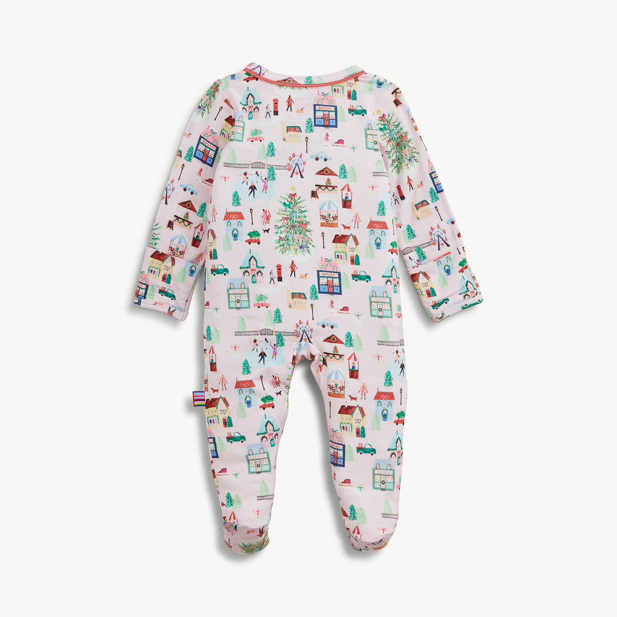 A baby footed sleeper with long sleeves and legs, featuring a colorful winter village print on a white background, shown against a light gray studio backdrop.