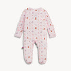 A baby footed sleeper in light pink with an all-over print of teddy bears, snow globes, and snowman faces in darker pink, purple, and brown, shown flat on a light off-white background.