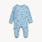 A baby's footed long-sleeve jumpsuit in light blue, featuring an all-over print of cartoon dogs in various sports poses on a plain off-white background.