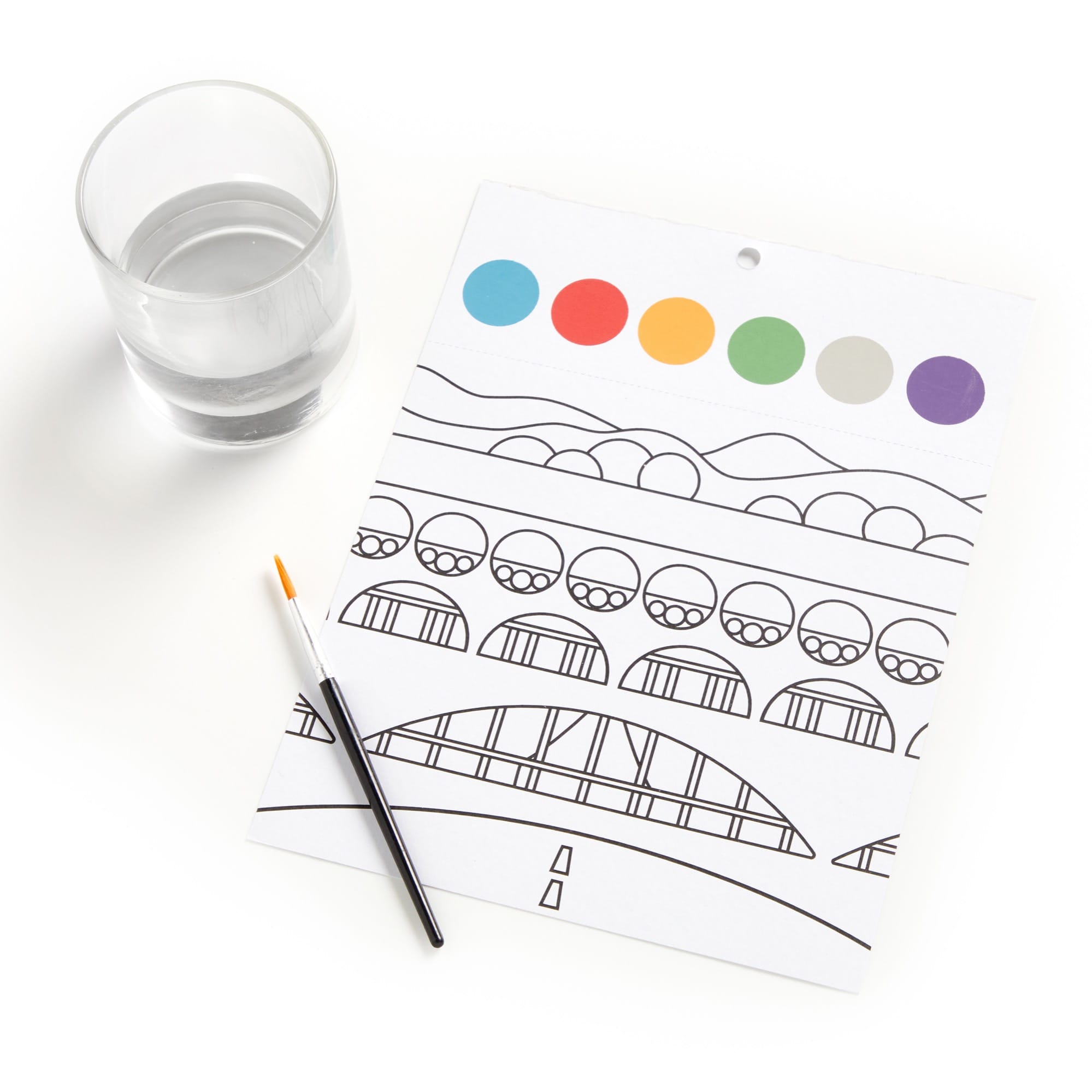 Coloring page with a bridge design, colored circles, and a glass of water on a white surface.