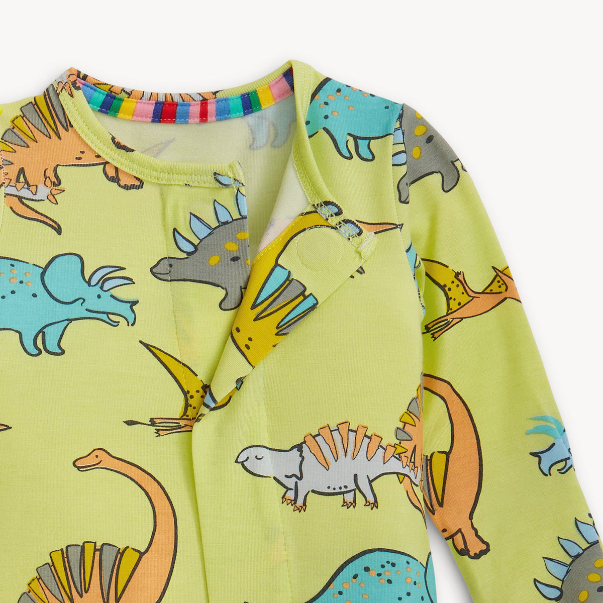 Children's long-sleeve shirt with colorful dinosaur pattern on a light green background