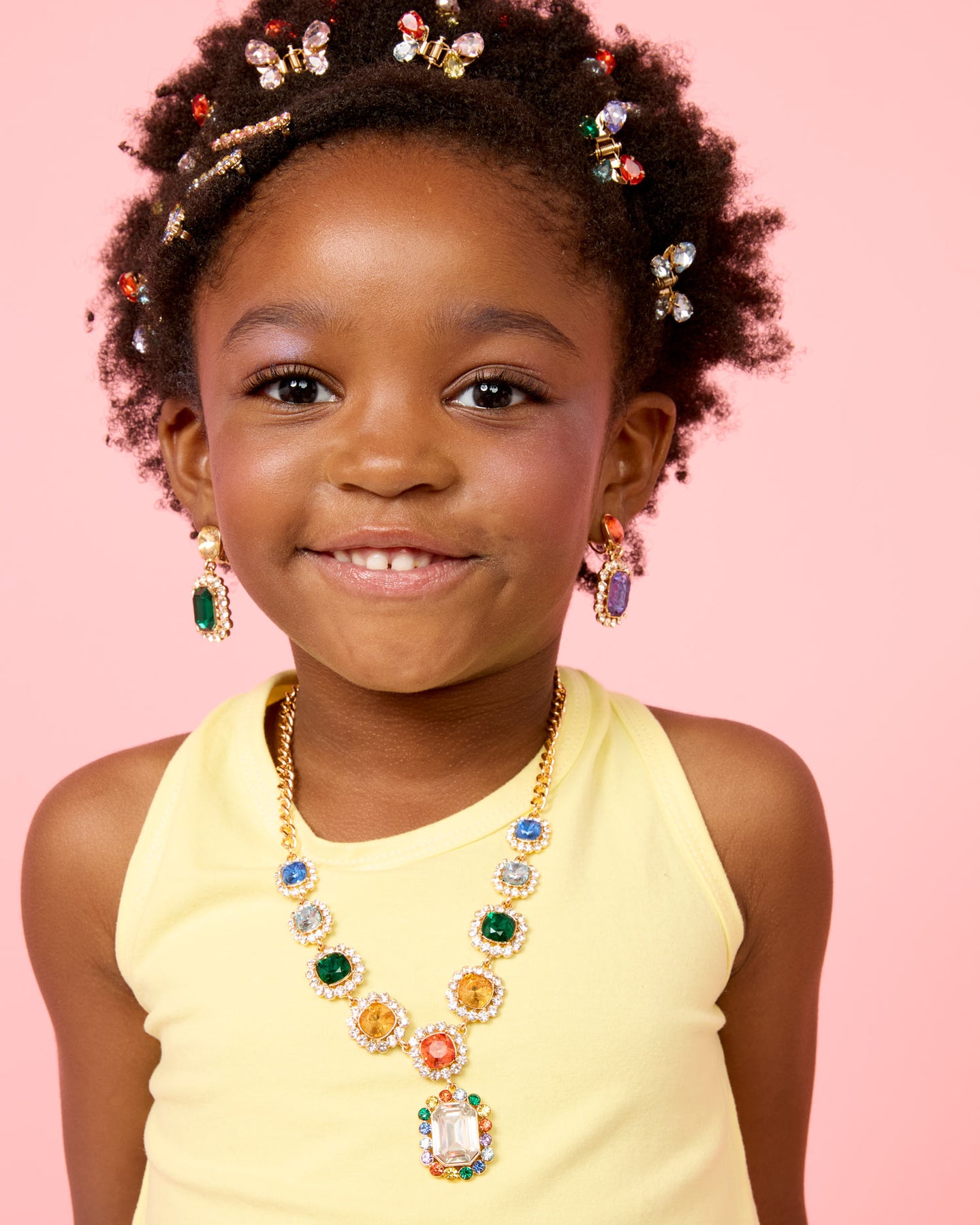 Young girl wearing colorful jewelry against a pink background