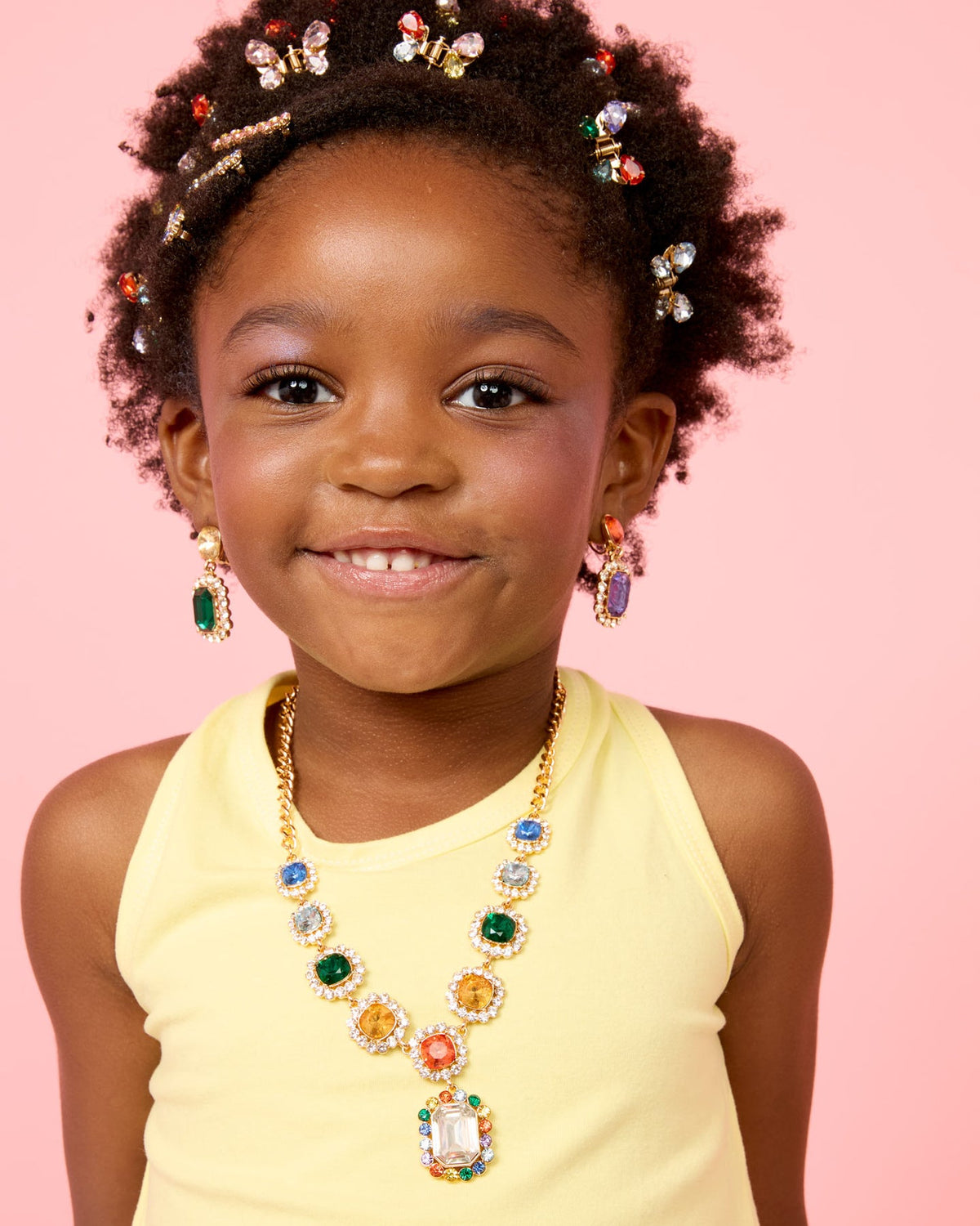 Young girl wearing colorful jewelry against a pink background
