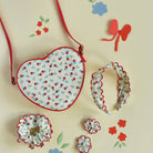 Heart-shaped fabric pouch with floral pattern on a light background with decorative elements.