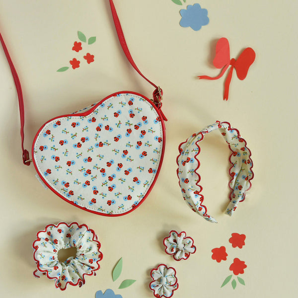 Heart-shaped fabric pouch with floral pattern on a light background with decorative elements.