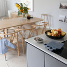 A blue silicone baby food freezer tray with its lid resting on a kitchen counter next to a bowl of apples and a vase of sunflowers in the background.
