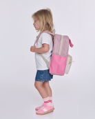 Child wearing a pink and beige backpack on a white background