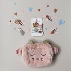 Pink fluffy pouch with gold accents and a card of hair clips on a light gray background with heart decorations.