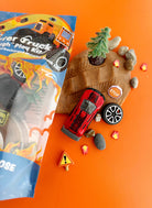 Toy truck and accessories on an orange background with packaging to the side.