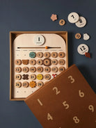 Wooden calendar toy with numbers and days of the week on a dark blue background