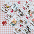 Collection of hair accessories on display with 'Rachahula' branding on a checkered background.