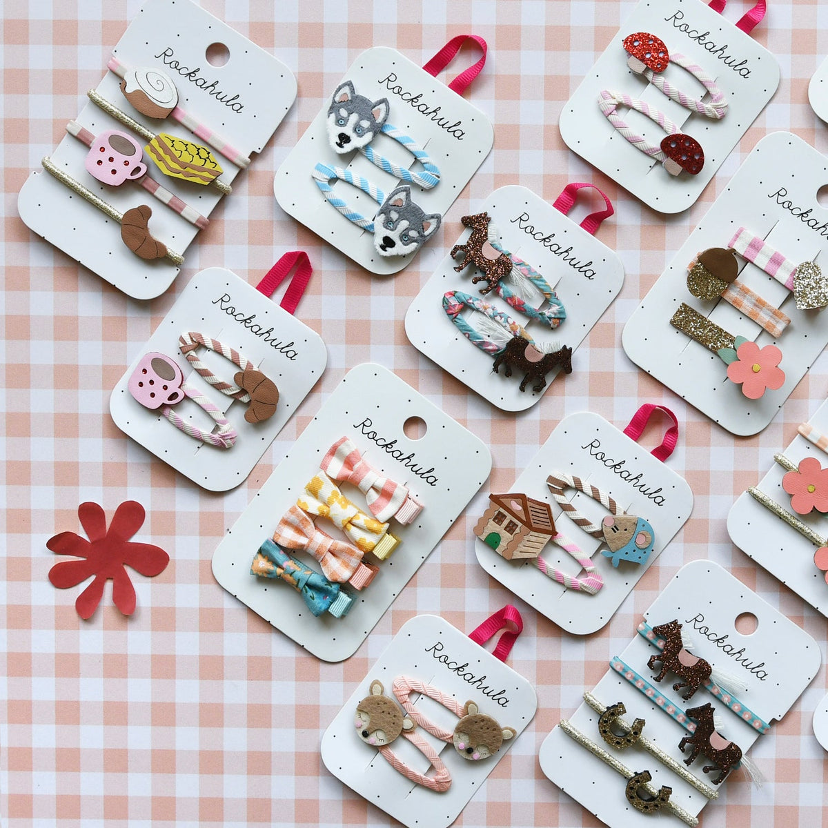 Collection of hair accessories on display with 'Rachahula' branding on a checkered background.