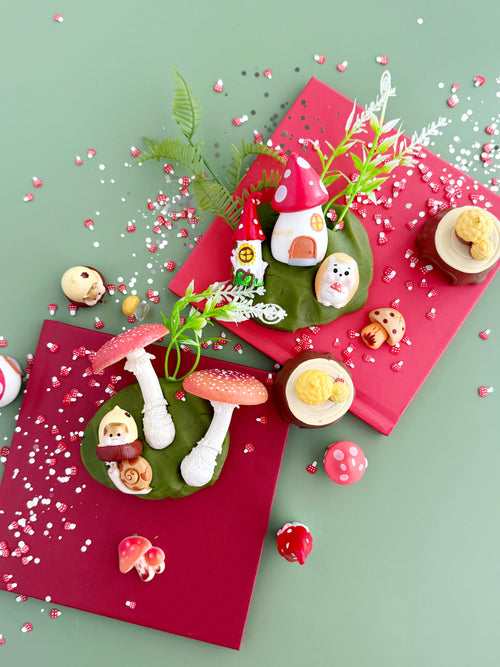 Decorative Christmas wreath with small figures and red and green colors on a light green background.