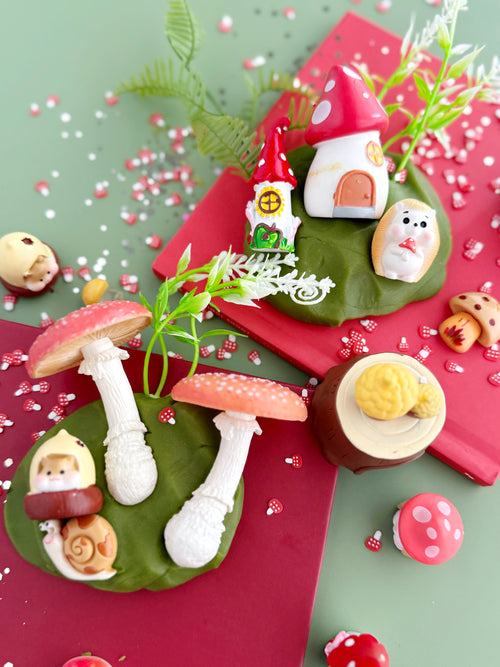 Decorative set of small figurines on a green base with red and pink accents.