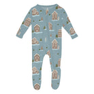A baby long-sleeve footed sleeper with a light blue winter village print featuring gingerbread houses, Christmas trees, and snow, shown on a plain white background.