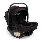 A profile view of a black MIXX Next + Pipa Aire RX Travel System by Nuna infant car seat featuring a brown leatherette carry handle and an extended canopy, set against a checkered transparent background.