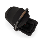 A close-up profile view of a black MIXX Next + Pipa Aire RX Travel System by Nuna infant car seat showing the brown leatherette handle wrap, set against a checkered transparent background.
