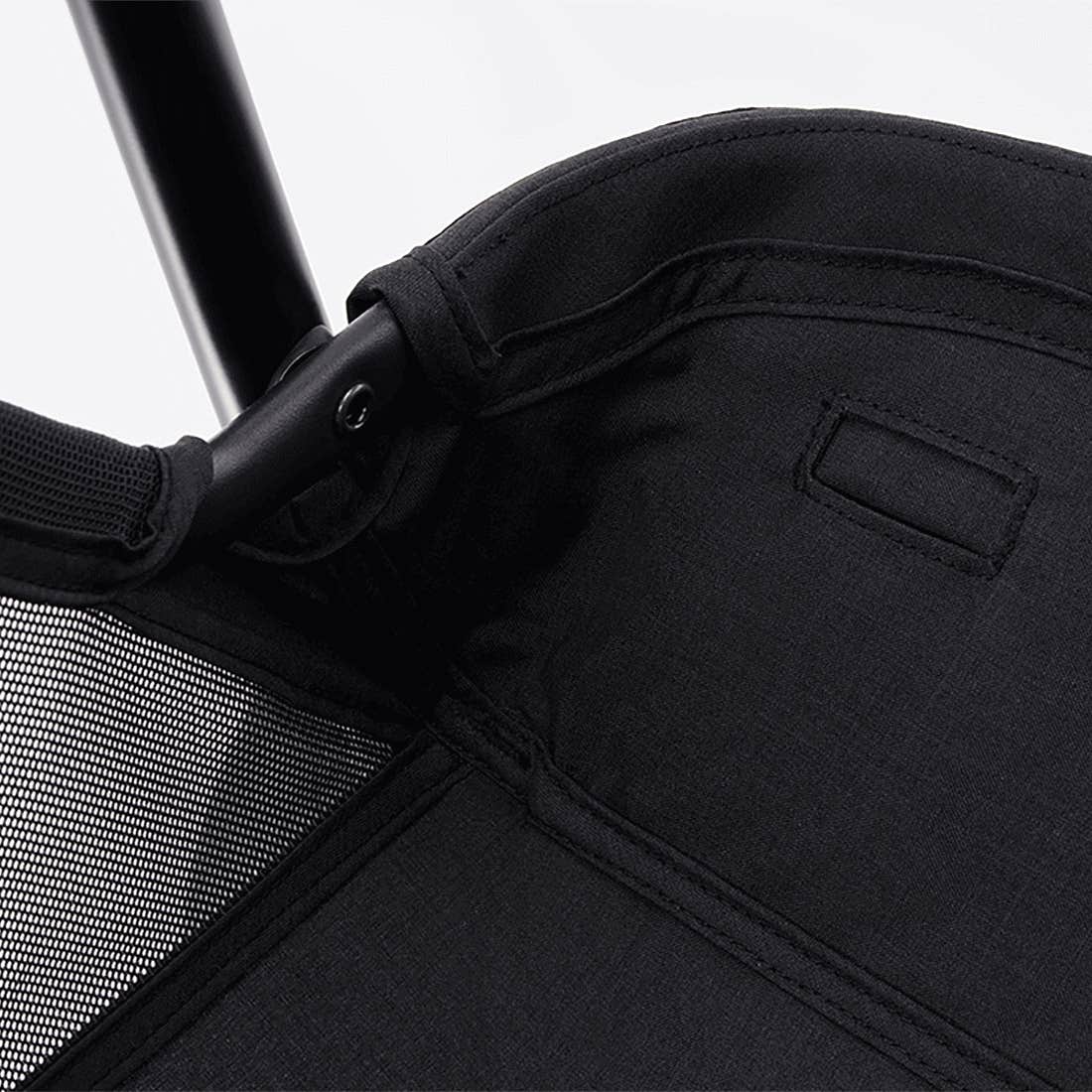 Close-up of a black stroller with mesh side panel on a white background