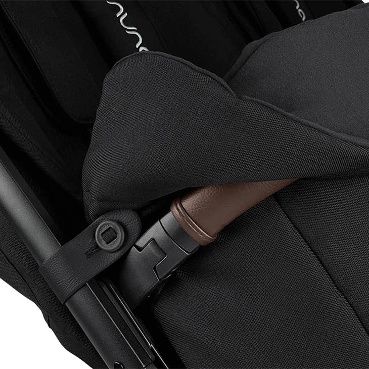 Close-up of a black stroller with brown accents on a white background