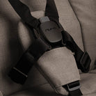 Close-up of a black seat belt buckle on a gray car seat with 'Nuna' branding.