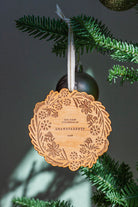 Wooden ornament with engraved design hanging on a Christmas tree branch.