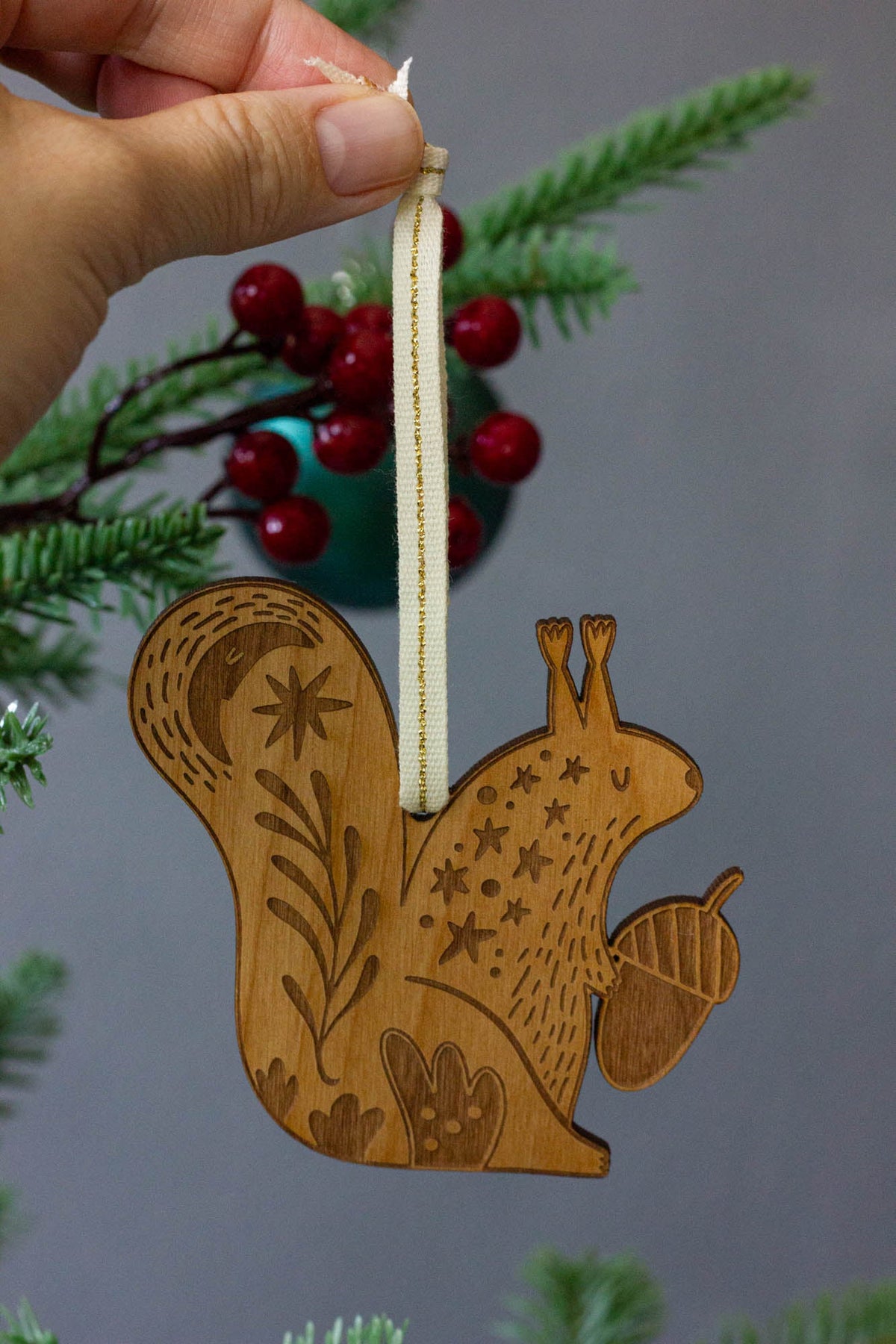 Wooden squirrel ornament with engraved details on a white background