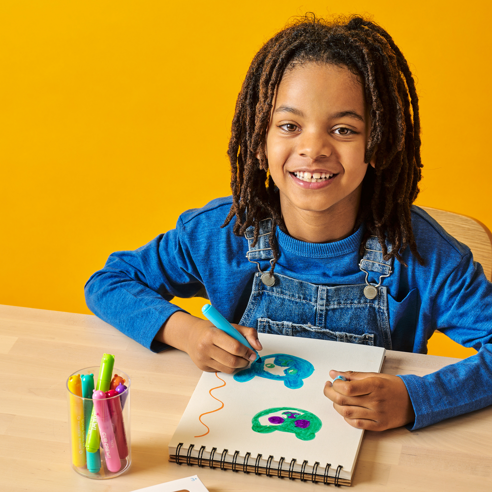 Child drawing with markers on a yellow background