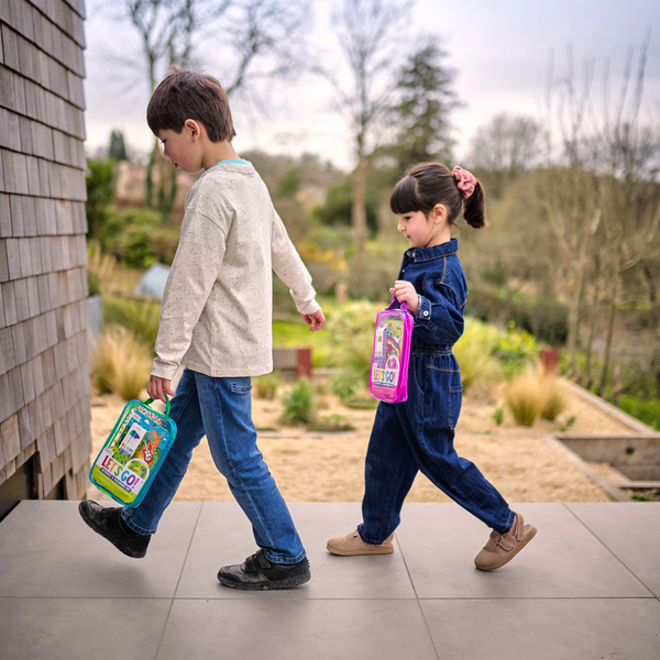 Two children walking outdoors with colorful lunch bags.