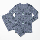 A two-piece pajama set featuring a long-sleeve top and matching pants in a dusty slate blue-gray color, decorated with an all-over pattern of woodland animals including deer, rabbits, foxes, and a penguin in dark navy and light blue-gray.