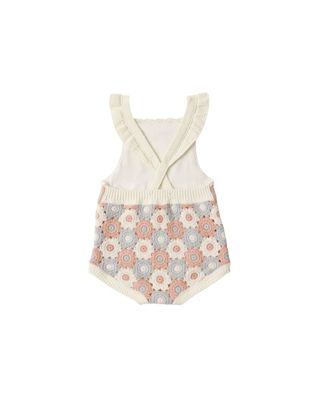 Baby romper with floral patterned bottom and white top on a white background