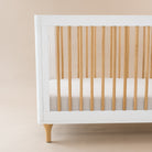 White crib with wooden sides on a beige background