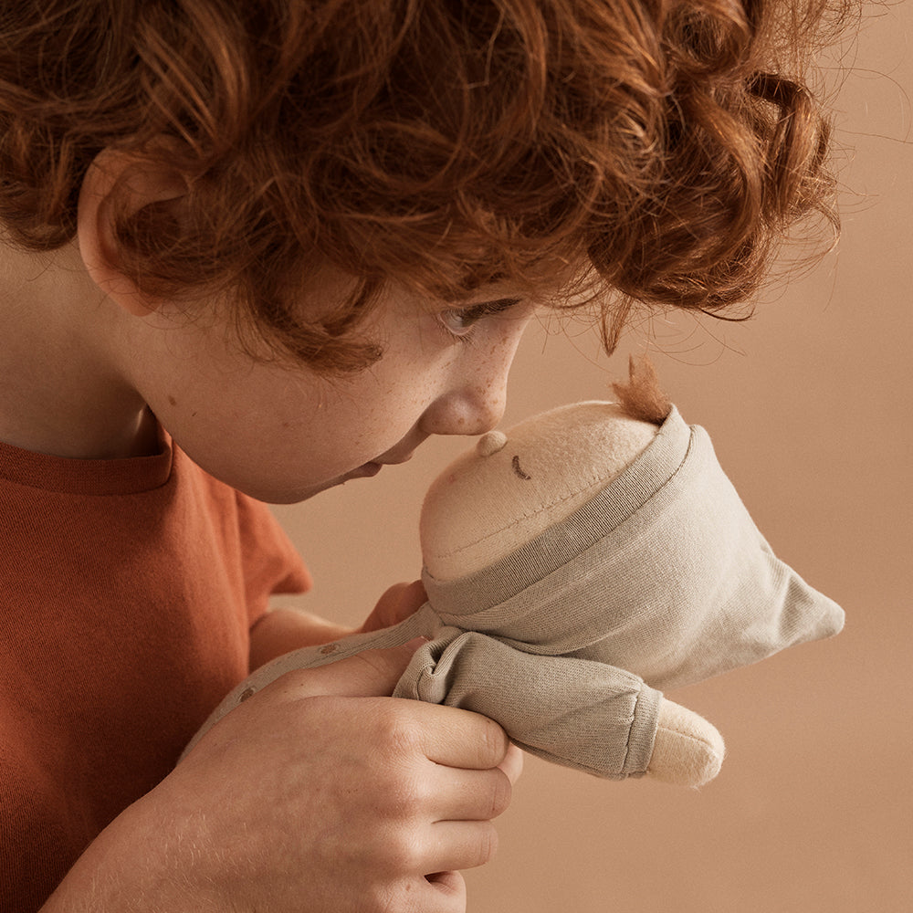 Child holding a soft toy against a warm brown background