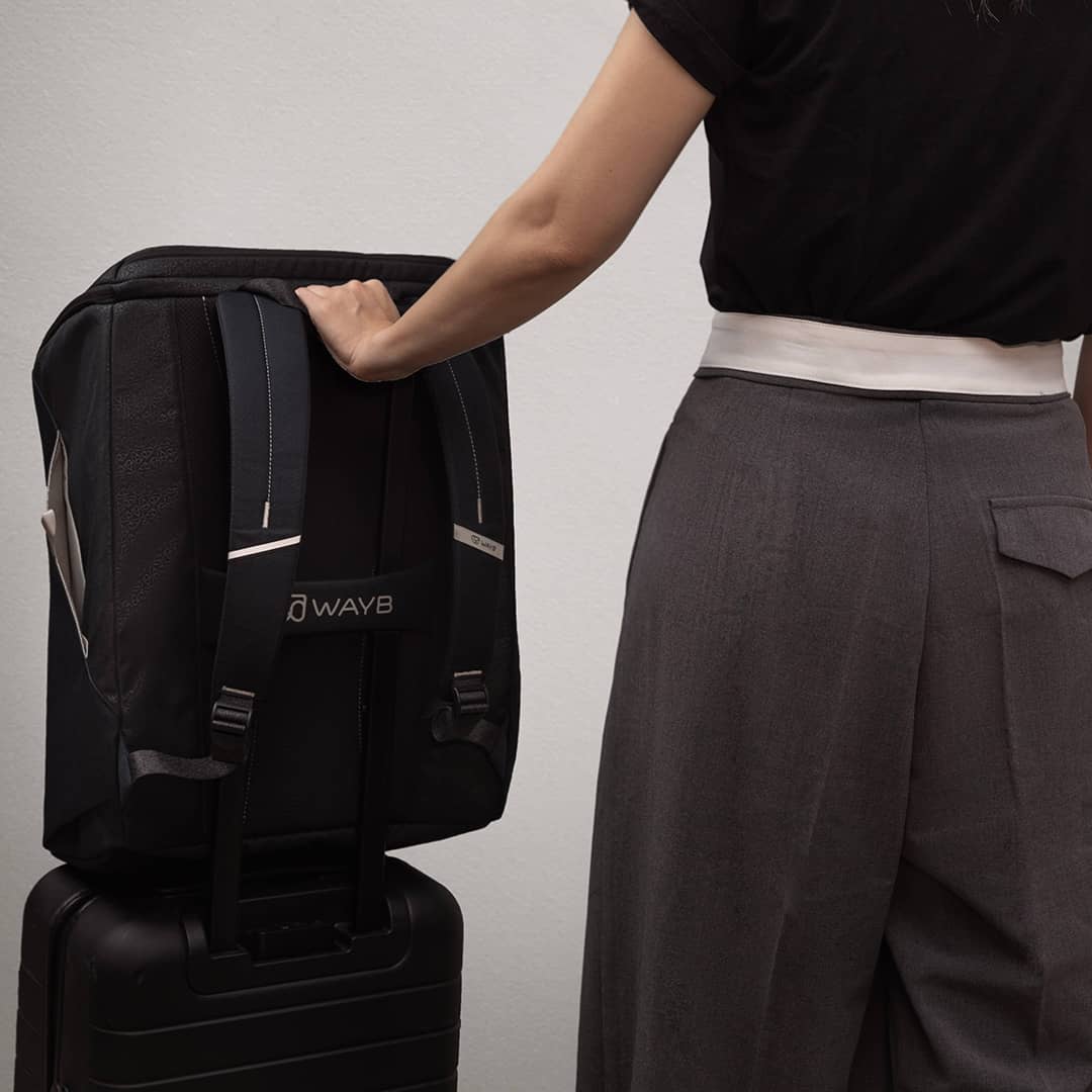 Person holding a black backpack with 'DWAY' branding against a plain background