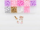 Princess Party DIY Bracelet Kit featuring an open compartment storage box filled with colorful pink, purple, and white round beads, alphabet letter beads, and gold spacer beads, alongside several gold charms including a bow, crown, and heart.