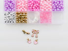Princess Party DIY Bracelet Kit featuring an open compartment storage box filled with colorful pink, purple, and white round beads, alphabet letter beads, and gold spacer beads, alongside several gold charms including a high heel shoe, bow, crown, and heart.