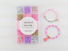 Princess Party DIY Bracelet Kit featuring a compartment storage box with a "stacked sweetly - Princess Party" label, filled with colorful beads, alphabet letter beads, and charms, next to two completed pink, purple, and gold beaded bracelets, including one spelling "PRINCESS" with a small crown and tassel charm.