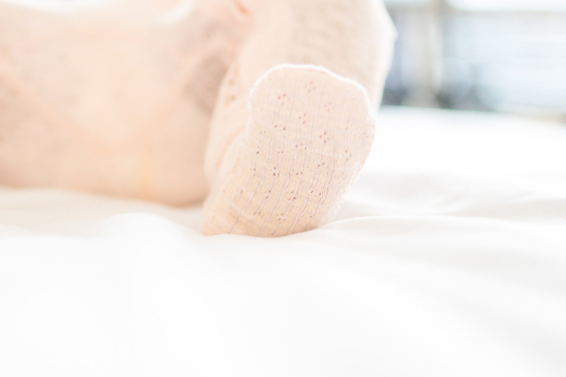 Close-up of a person's feet wearing white socks on a blurred background
