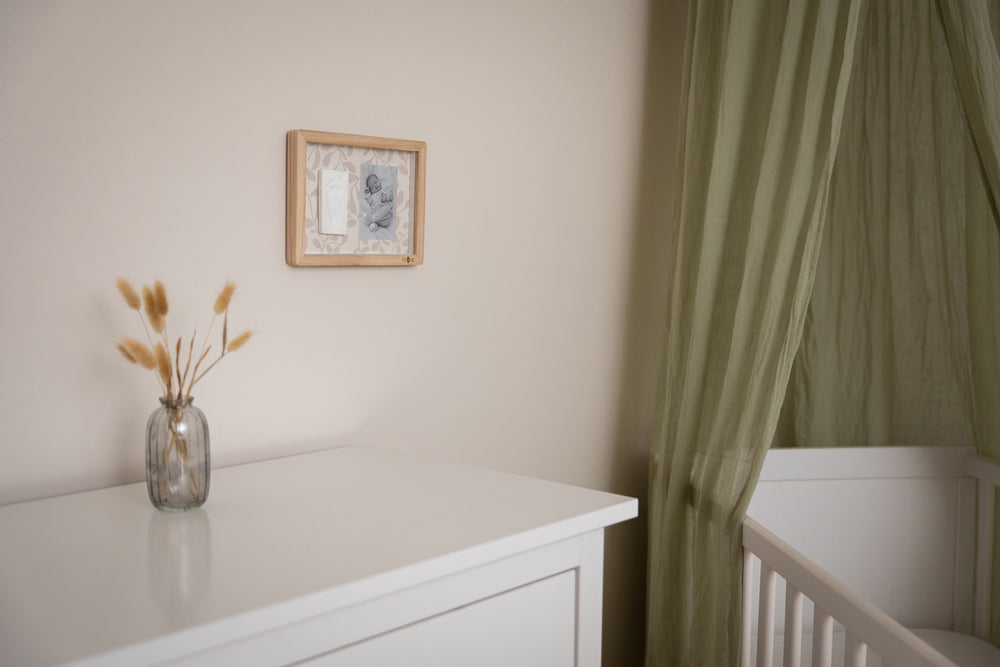 Nursery room with white dresser, crib, and framed picture on wall.