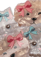 Decorative animal-shaped items on a plain white background: two cat faces with light blue bows and two dog faces with pink bows
