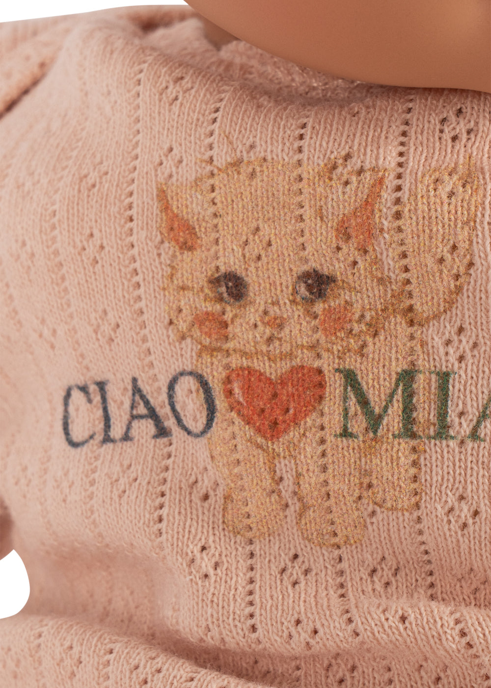 Close-up of a knitted pink sweater with a cat face graphic and the words 'CIAO MIAM' across the front, with part of a doll's face visible at the top.